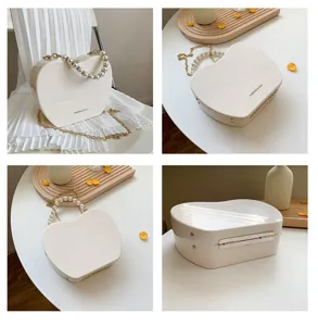 Heart-shaped pearl handle shoulder bag detail view, sleek hard shell crossbody purse design.