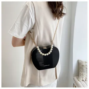 Detail view of stylish heart shaped bag with elegant pearl handle and gold chain strap design.