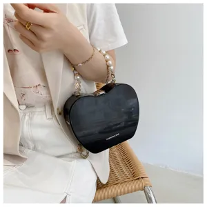 Close-up of the stylish heart-shaped handbag featuring delicate pearl and chain handle details.