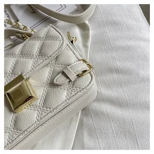 White quilted crossbody bag detail with gold hardware, elegant chain strap and chic square lock.