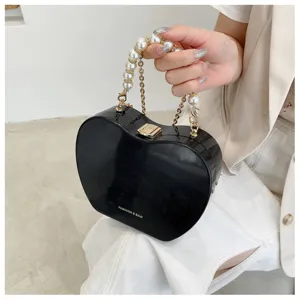 Black heart shaped hard shell handbag with pearl chain handle, stylish detail view.