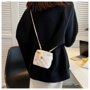 Detailed shot of a stylish white quilted vanity crossbody bag with gold chain strap.