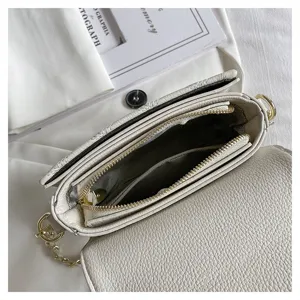 Close-up view of the white leather shoulder bag interior, showing double zipper compartments.