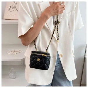 Black quilted vanity bag detail featuring gold chain strap and chic camellia decor.