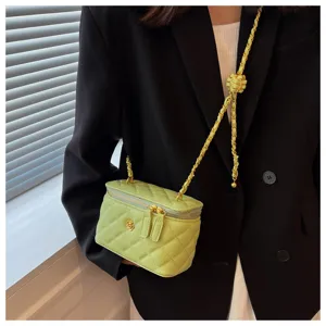 Detail view of a light green quilted chain vanity box bag with elegant gold hardware.