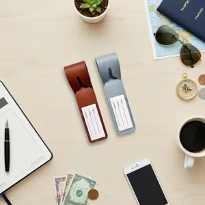 Detailed view of PU leather luggage tags in brown and blue with card inserts on wooden desk.