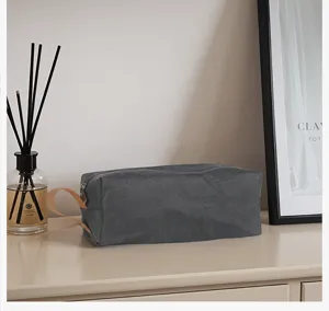 Detalle de bolsa cosmética de papel kraft lavado gris, estuche de almacenamiento portátil.