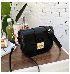 Detailed view of the stylish black leather saddle bag featuring a metal lock and strap.