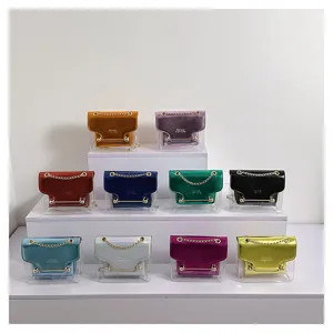 Transparent small square bag detail showing colorful metallic flaps and stylish chain design.