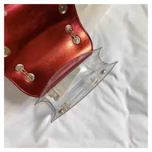 Clear PVC shoulder bag detail showing red metallic flap and gold chain strap close-up.