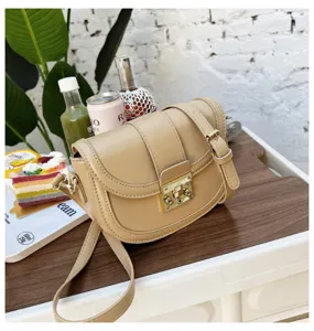 Stylish women's beige leather saddle bag with chic metal lock and adjustable crossbody strap.
