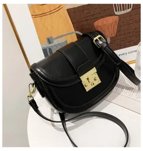 Closeup detail of black leather saddle bag featuring elegant golden metal lock and shoulder strap.