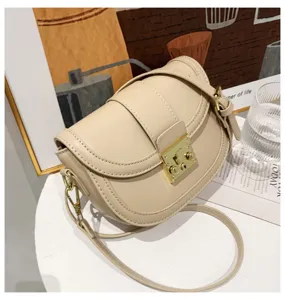 Beige stylish saddle bag for women, elegant fashion shoulder bag with metal lock closure.