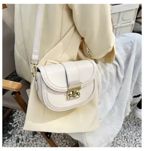 Detailed view of a elegant white saddle bag with chic metal lock and shoulder strap.