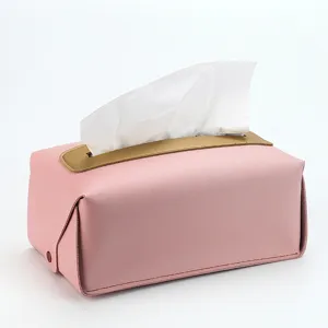 Gros plan sur la boîte à mouchoirs en cuir rose avec détail doré et texture raffinée.
