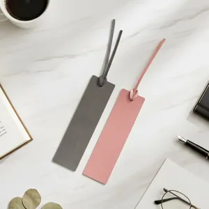 Detailansicht minimalistischer Lederlesezeichen in Grau und Rosa mit Kordel auf Marmor.