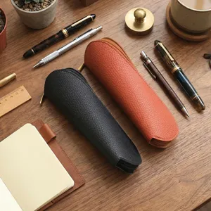 Vista detallada de estuches de cuero texturizado en un escritorio de madera con accesorios.