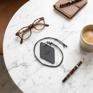 Vista detallada del soporte de gafas de cuero negro con cordón para uso portátil.