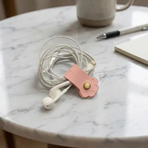 Roze kattenpoot leer kabelwinder detailweergave met metalen drukknop voor oortelefoon.