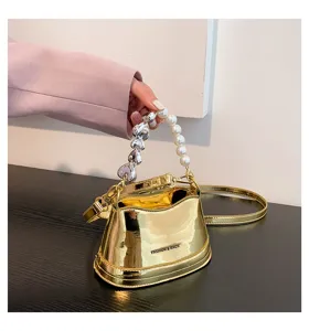 Detailaufnahme der glänzenden goldenen Eimerhandtasche mit Perlen- und Herzgriff.
