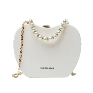 White apple-shaped shoulder bag with pearl handle and chic gold chain strap for women.