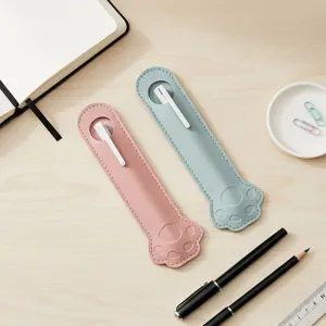 Close-up view of cute animal paw PU leather pen sleeves in pink and blue on a wooden desk.