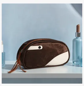 Close-up detail of the brown and white PU leather cosmetic bag with a chic zipper tassel.