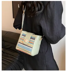 Detail view of women woven bucket shoulder bag in green with colorful pattern and wide strap.