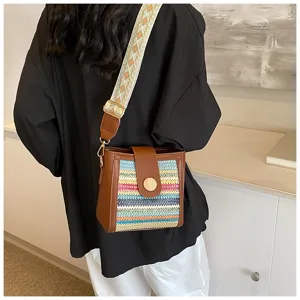 Detailed view of the woven bucket bag with wide strap and brown leather trim styled indoors.