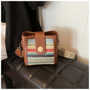 Chic woven bucket bag featuring brown leather trim, wooden button closure, and stylish wide strap.