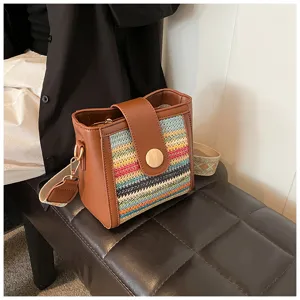 Detailed shot of the woven straw bucket bag showing colorful pattern and brown leather trim.