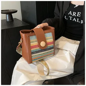 Stylish women bucket bag featuring brown PU leather and colorful woven straw with wide strap.