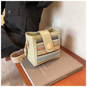 Detail shot of the stylish woven shoulder bag with wide strap and wooden button closure.