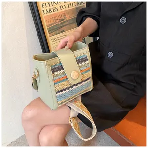 Detailed view of stylish woven bucket bag featuring green leather trim and wide patterned strap.