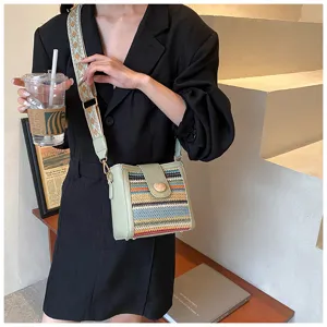Woven crossbody bucket bag for women, stylish shoulder bag with wide strap and colorful design.