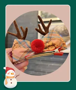 Christmas reindeer antlers hair clip, detailed view of plaid bow and red plush pom-pom.