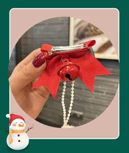 Christmas children red hair clip with bow, bell and pearl chain, festive hair accessory detail.