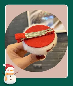 Detalle de pinza de pelo navideña con pinza de pico rojo y base de peluche suave.