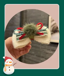 Christmas bow hair clip with cute plush ball, festive children hair accessory detail view.