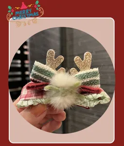 Detailed close-up of Christmas bow hair clip with cute reindeer antlers and white pom-pom.