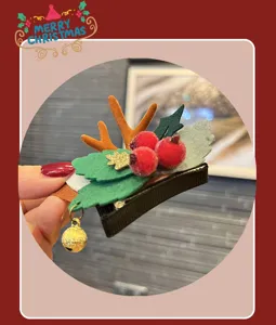 Christmas reindeer hair clip detail view showing festive antlers, red berries and cute bell ornament.
