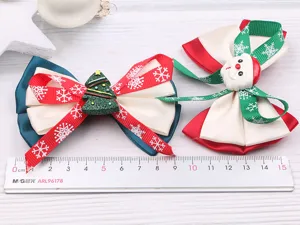 Vue détaillée de pinces à cheveux nœud de Noël avec mignons ornements de Père Noël et sapin.
