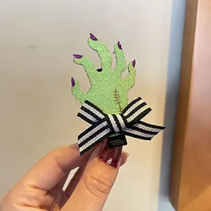 Nahaufnahme der Halloween grüne Zombie Hand Haarklammer mit schwarzweißer Schleife.