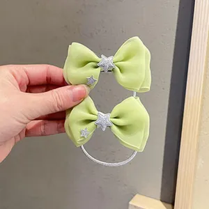 Détail d'élastique à cheveux nœud en tulle vert avec étoile scintillante et texture douce.