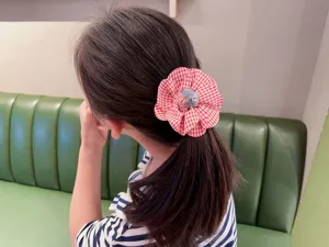 Primer plano de coletero de tela con flor de cuadros rojos, accesorio de pelo diario bonito.