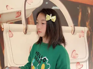 Vue detaillee de la pince a cheveux noeud en tissu a pois verts portee par enfant, style frais.