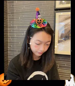 Detail shot of a girl wearing a Halloween witch hat headband with pumpkin and skull design.