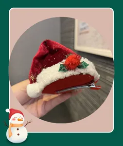 Detailed view of red plush Christmas hat hair clip, showing velvet texture and pom-pom.