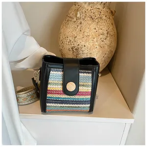 Detailed view of women's woven bucket bag with black leather and colorful patterns.