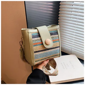 Close-up detail of the stylish woven crossbody bag with green leather trim and wooden button.